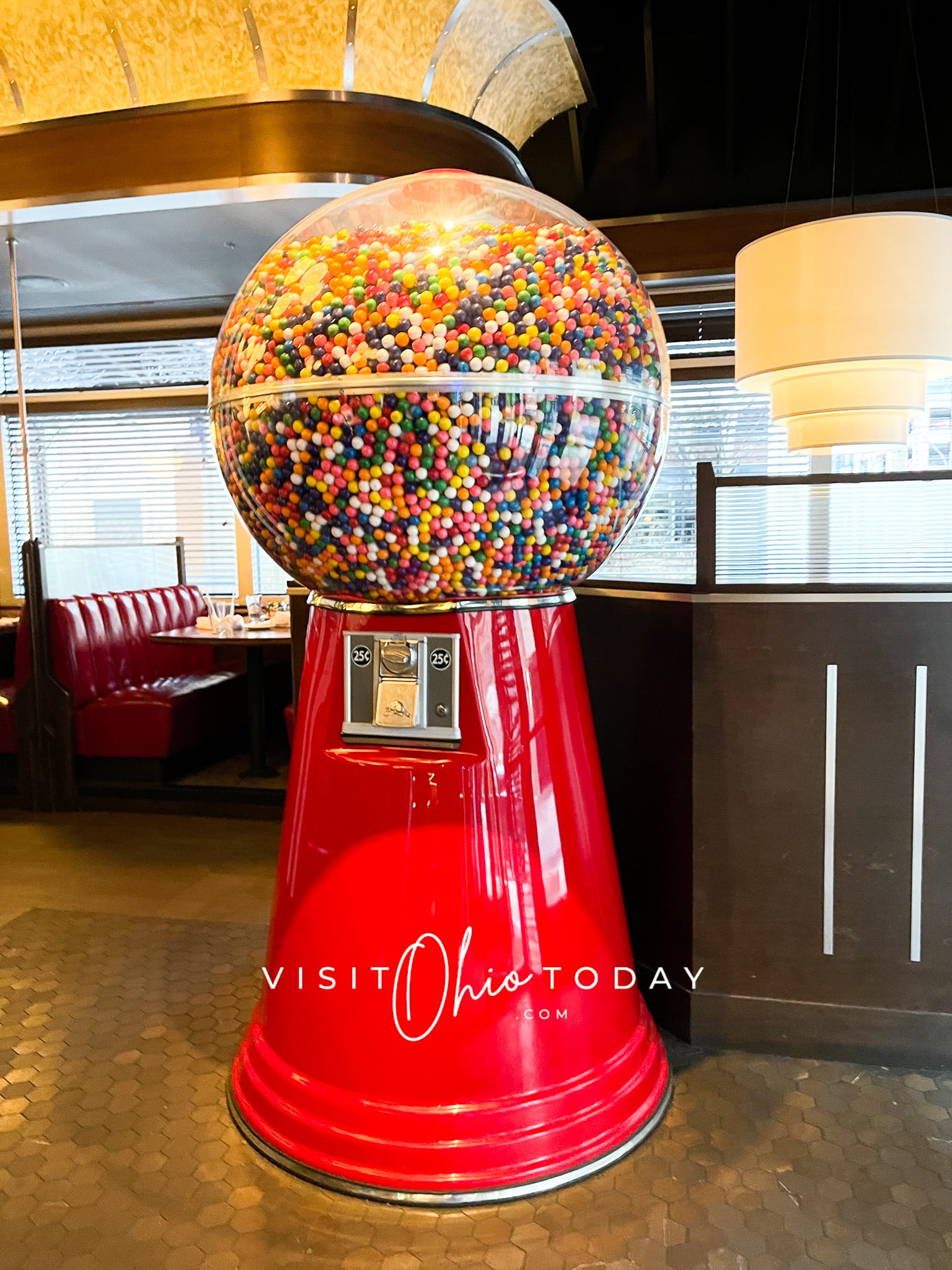 giant gumball machine with red on bottom and gumballs on top