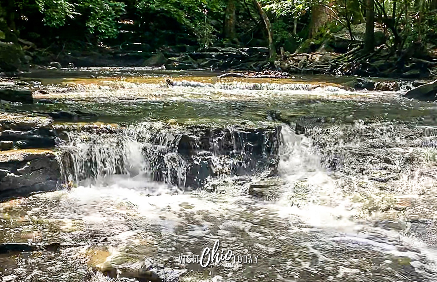 Water cascading over rocks. At the top are lots of trees with green leaves. Photo credit: Cindy Gordon of VisitOhioToday.com