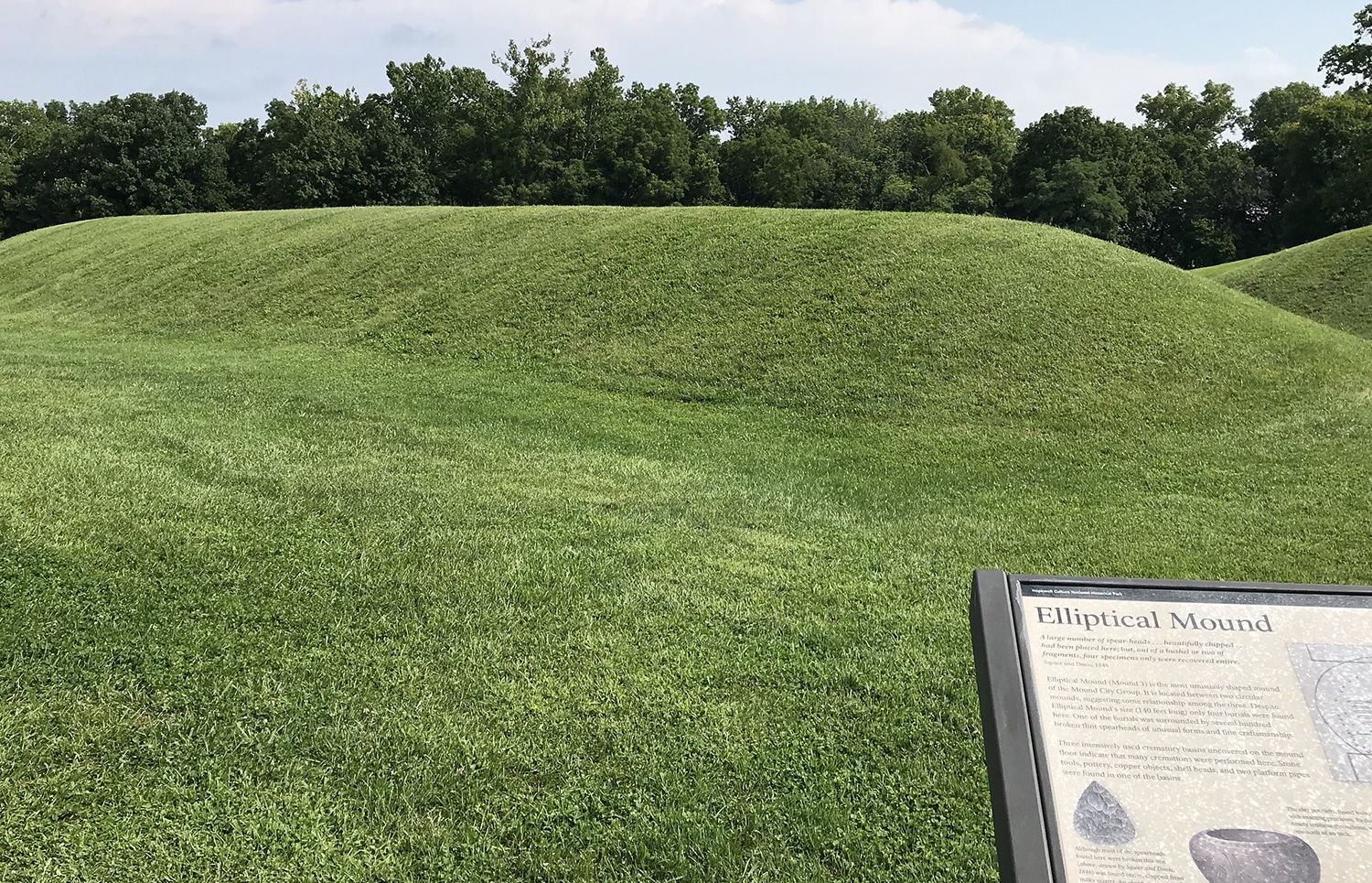 horizontal photo of an elliptical mound in chillicothe ohio, with trees in the background