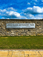 A metal plaque with the words John Glenn Astronomy Park attached to a stone wall