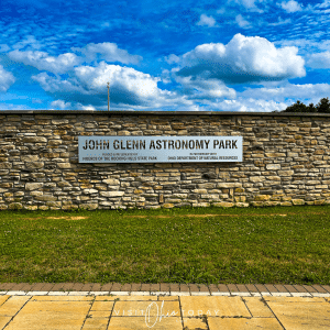 A metal plaque with the words John Glenn Astronomy Park attached to a stone wall