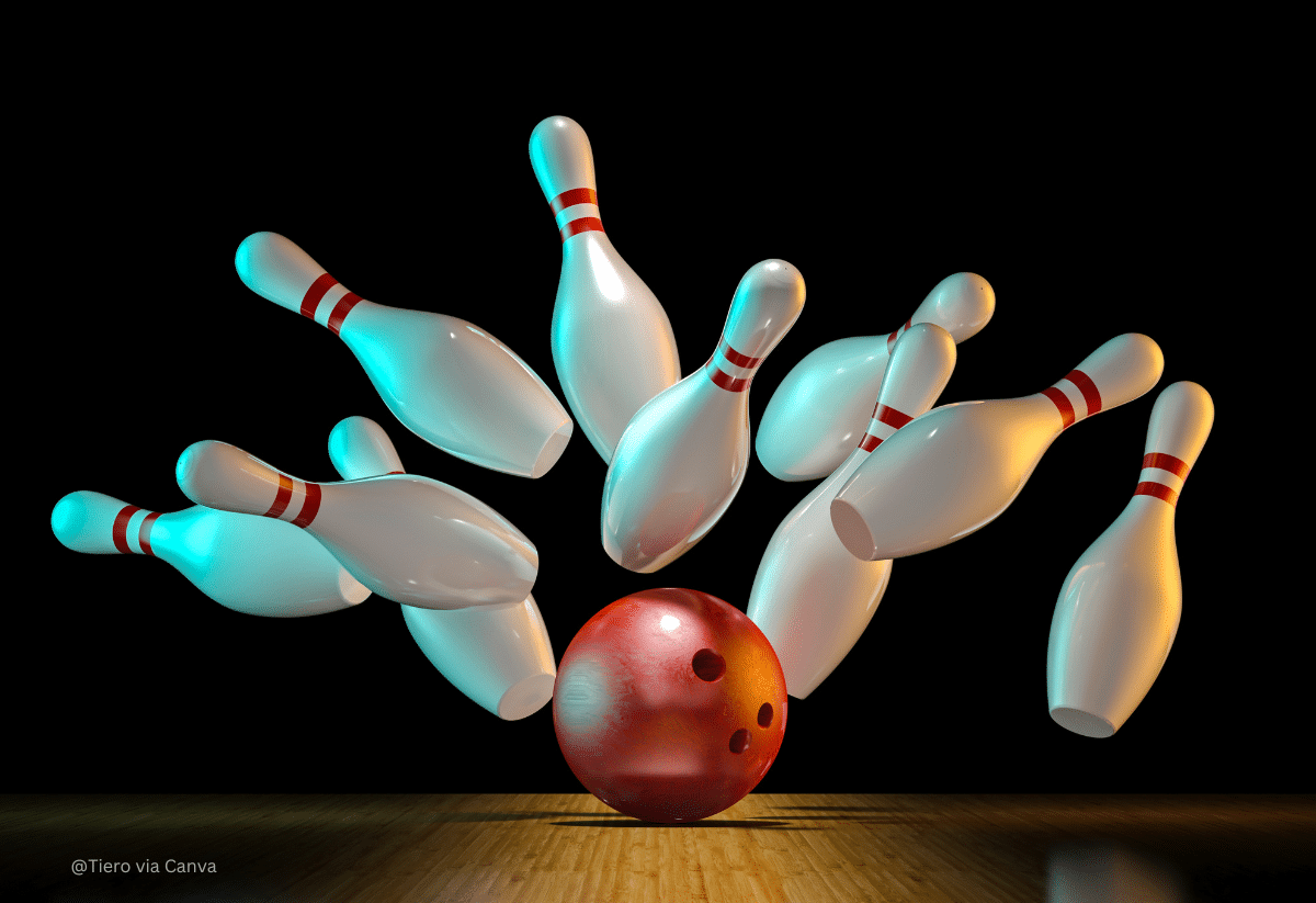 horizontal photo of the moment of the ball hitting the pins for a strike at a bowling alley