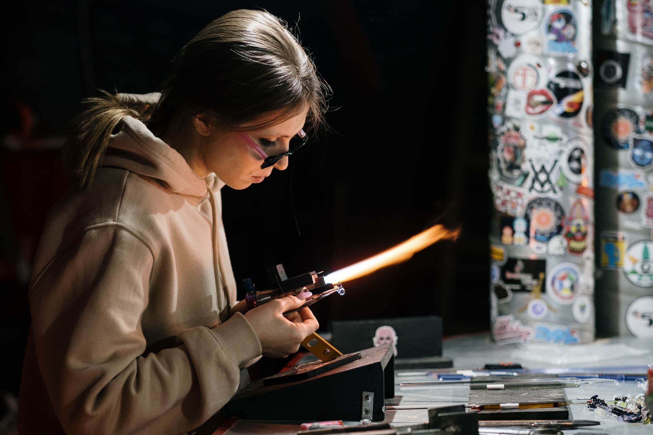 Horizontal picture of a female using glass-blowing equipment
