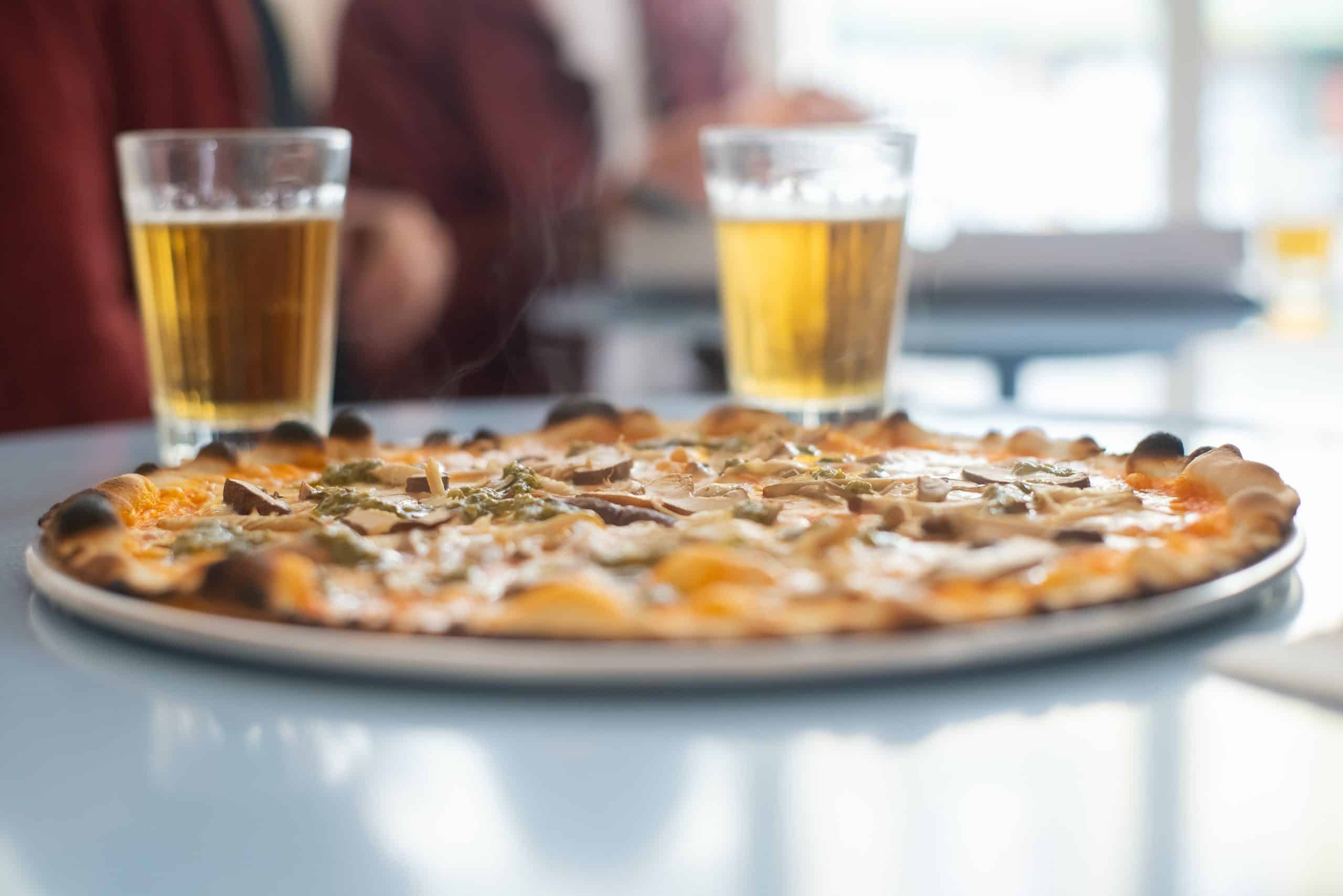 Pizza on a plate with two glasses of beer