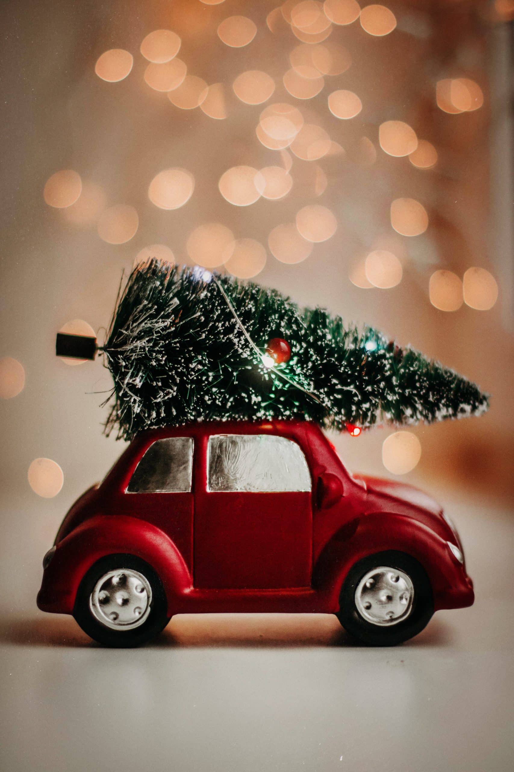 A small red toy car with a christmas tree on top