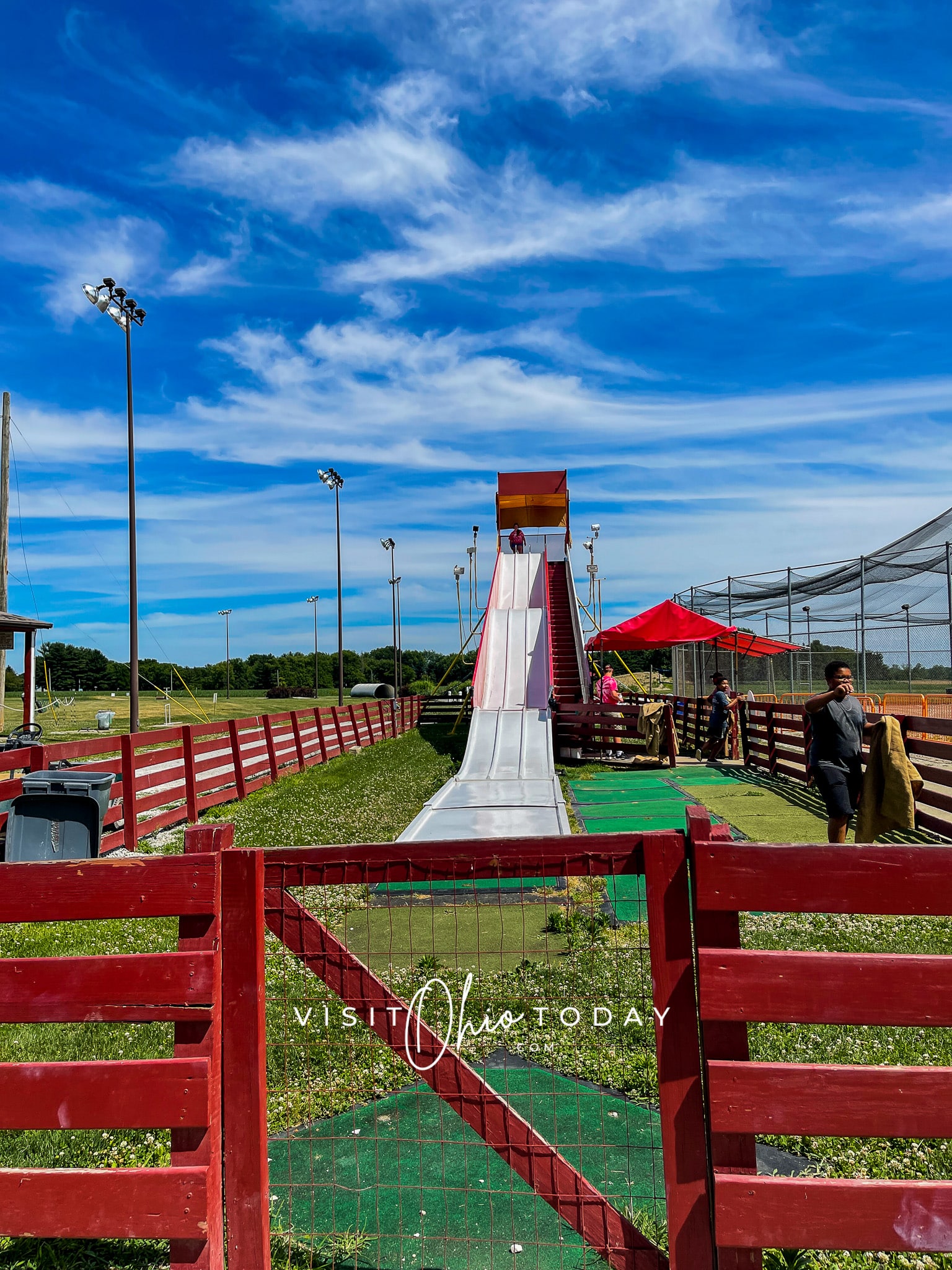 Vertical photo of a slide. There is a red fence all around.