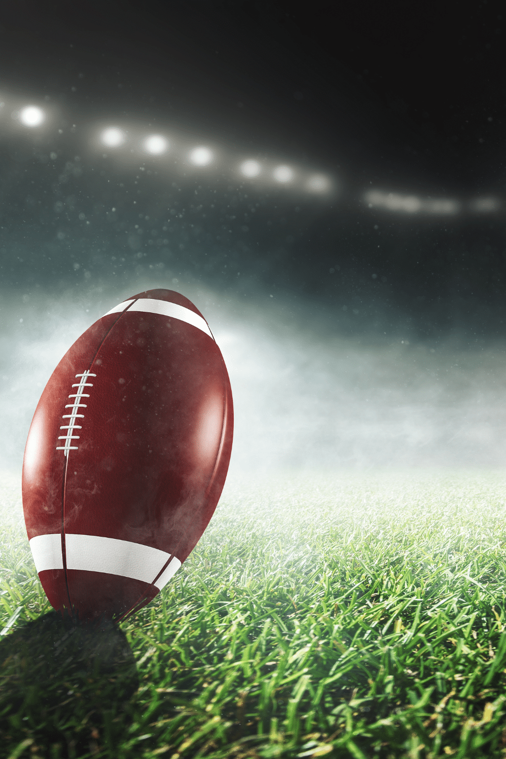 A football propped up in grass on a football field