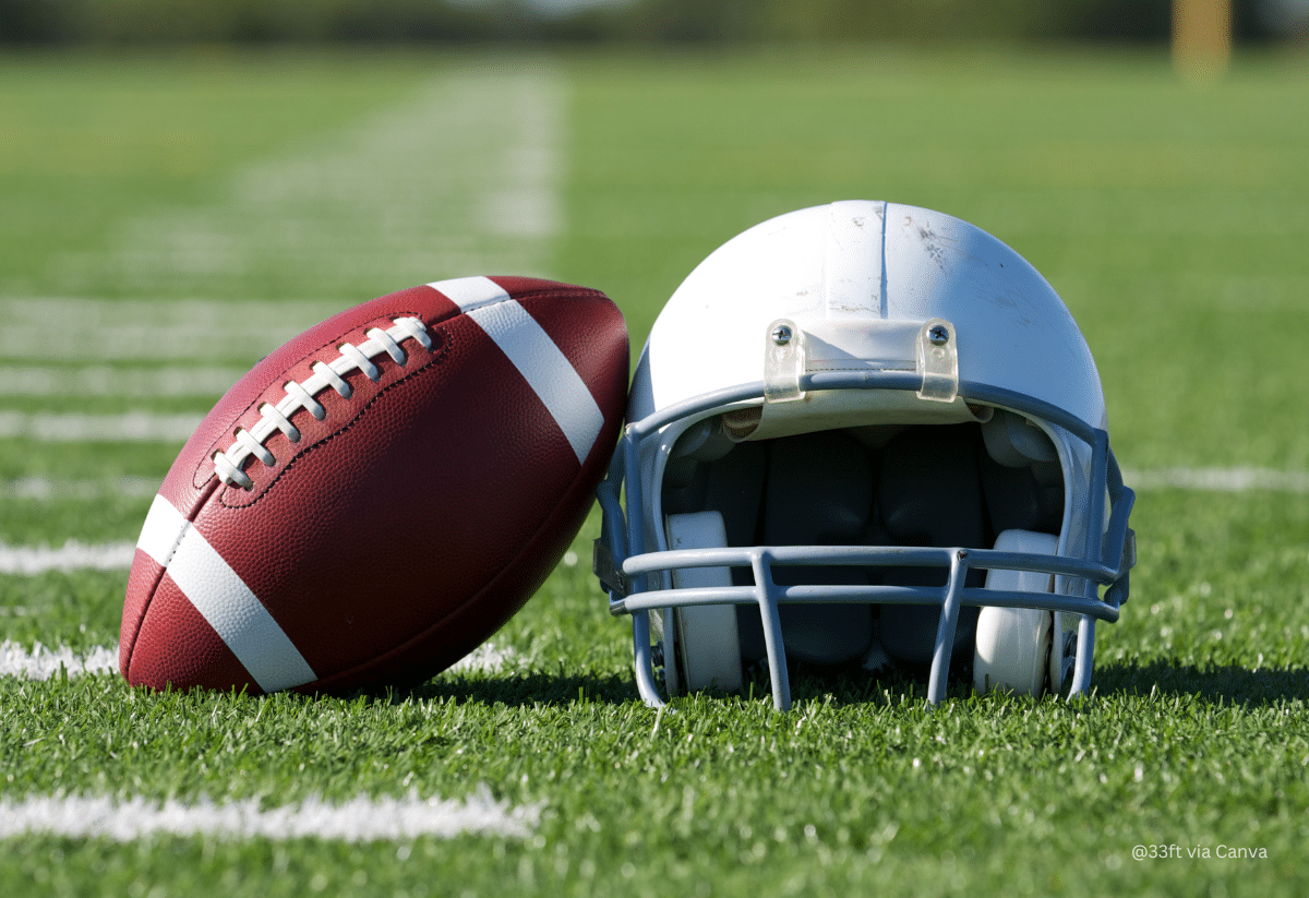 horizontal photo of a football and a football helmet on a football field