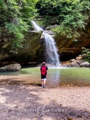 square photo of the waterfall at old man's cave with a boy standing in the foreground