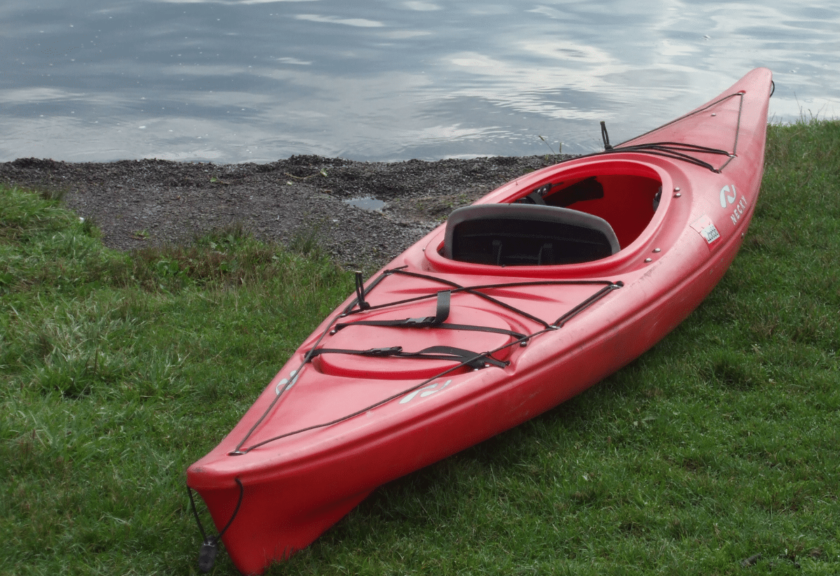 horizontal photo of a red kayak on a grassy bank