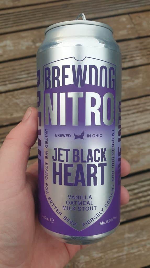 vertical photo of a hand holding a can of BrewDog Nitro Jet Black Heart, vanilla oatmeal milk stout