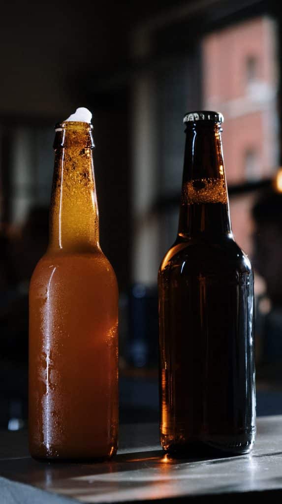 vertical photo of two beer bottles on a table, one brown, one black. (Breweries in Ohio)