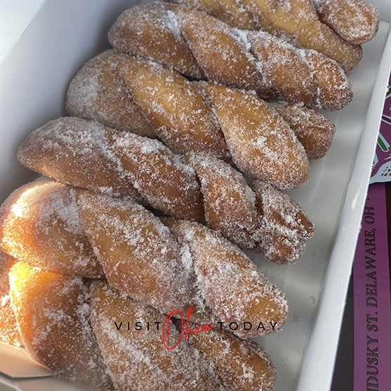 square photo showing a box of 6 twisted, sugared donuts
