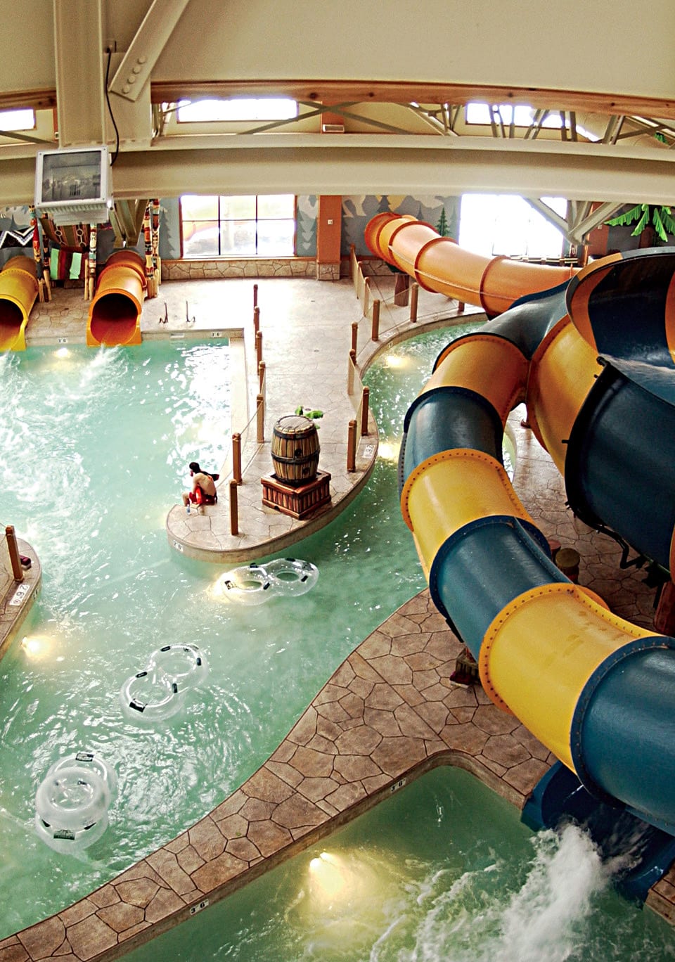 vertical photo showing a covered water chute and a swimming pool at one of the great wolf lodges indoor water parks 