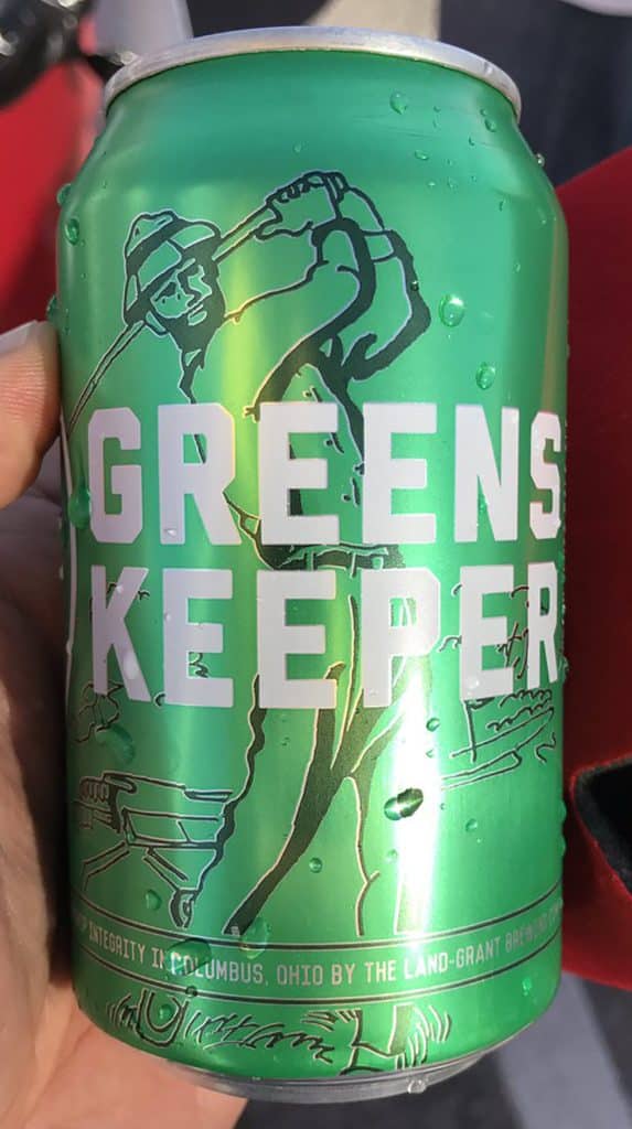 vertical photo showing a hand holding a can of land-grant brewing greenskeeper IPA (Breweries in Ohio)