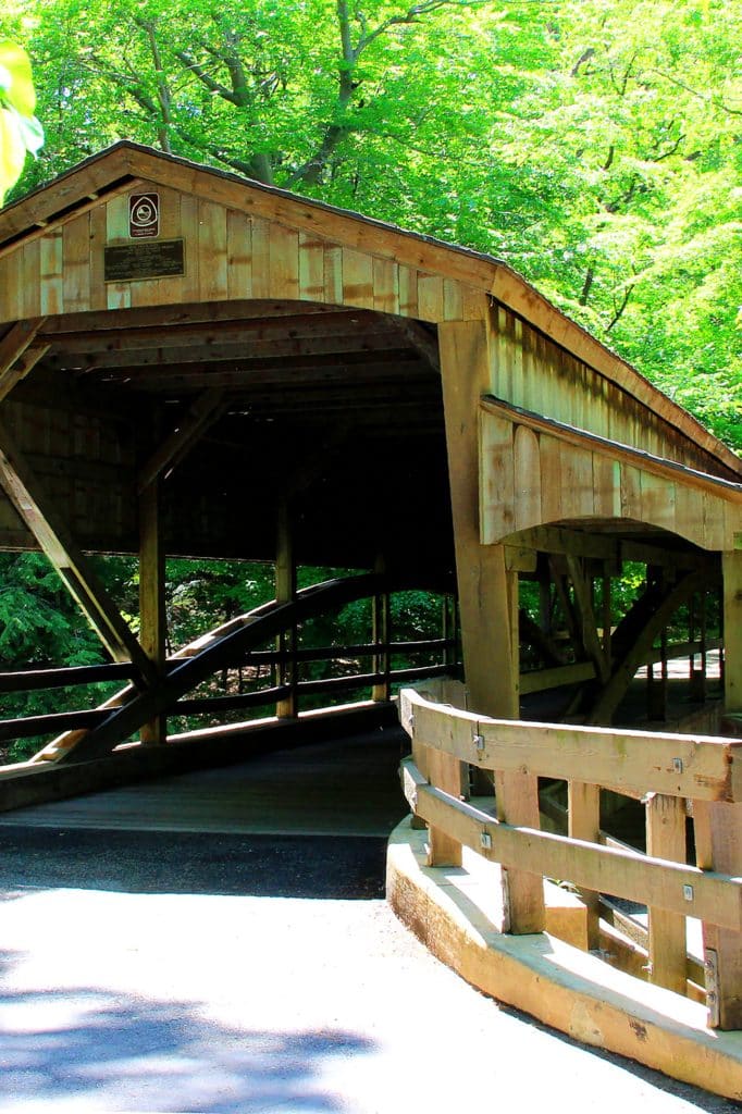 vertical photo of lanterman's mill covered bridge showing the road to and across the bridge and trees in the background