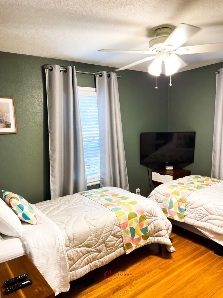 green walls, two twin beds with white spreads and wooden floors