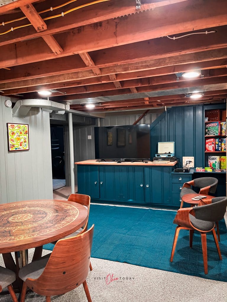 basement game room, showing a retro game table blue rug and large tv