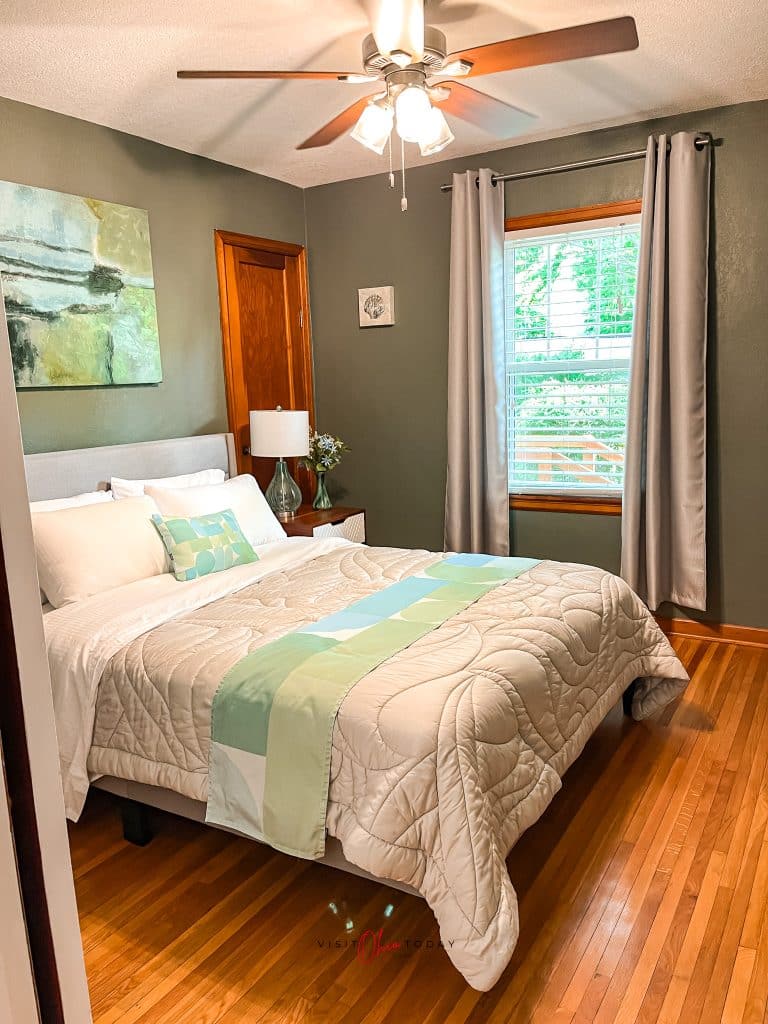 wooden floors, green walls, window with long curtains, white bedspreads