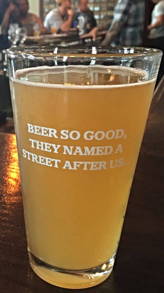 vertical photo of a large glass of beer with the words 'beer so good they named a street after us' on the glass (Breweries in Ohio)