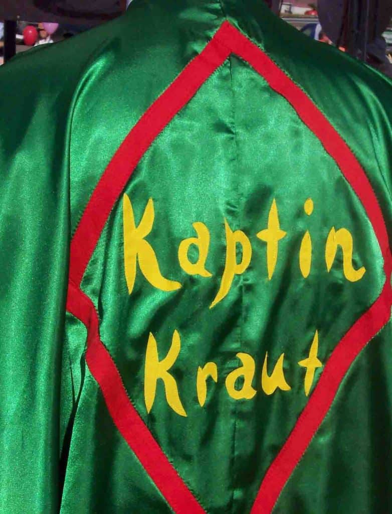 vertical photo of a person with a green cape with kaptin kraut in yellow letters on the back (fall festivals in ohio)