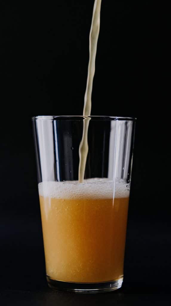 vertical photo of a glass of beer being poured. On a black background (breweries in ohio)