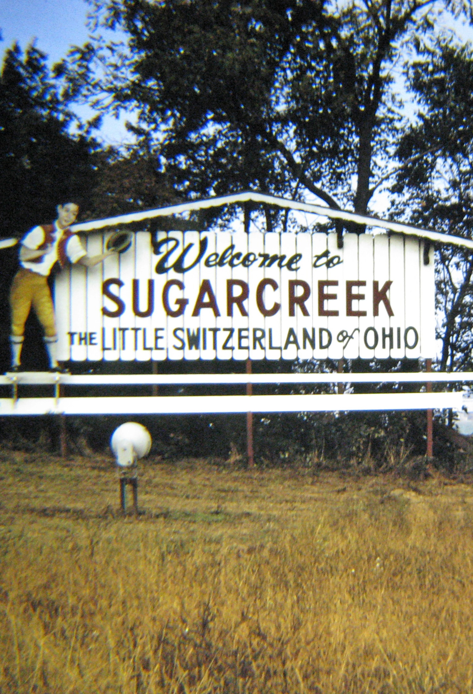 vertical photo of a white wooden welcome sign that reads: welcome to sugarcreek, the little switzerland of ohio Image credit: Russ Glasson on Flickr