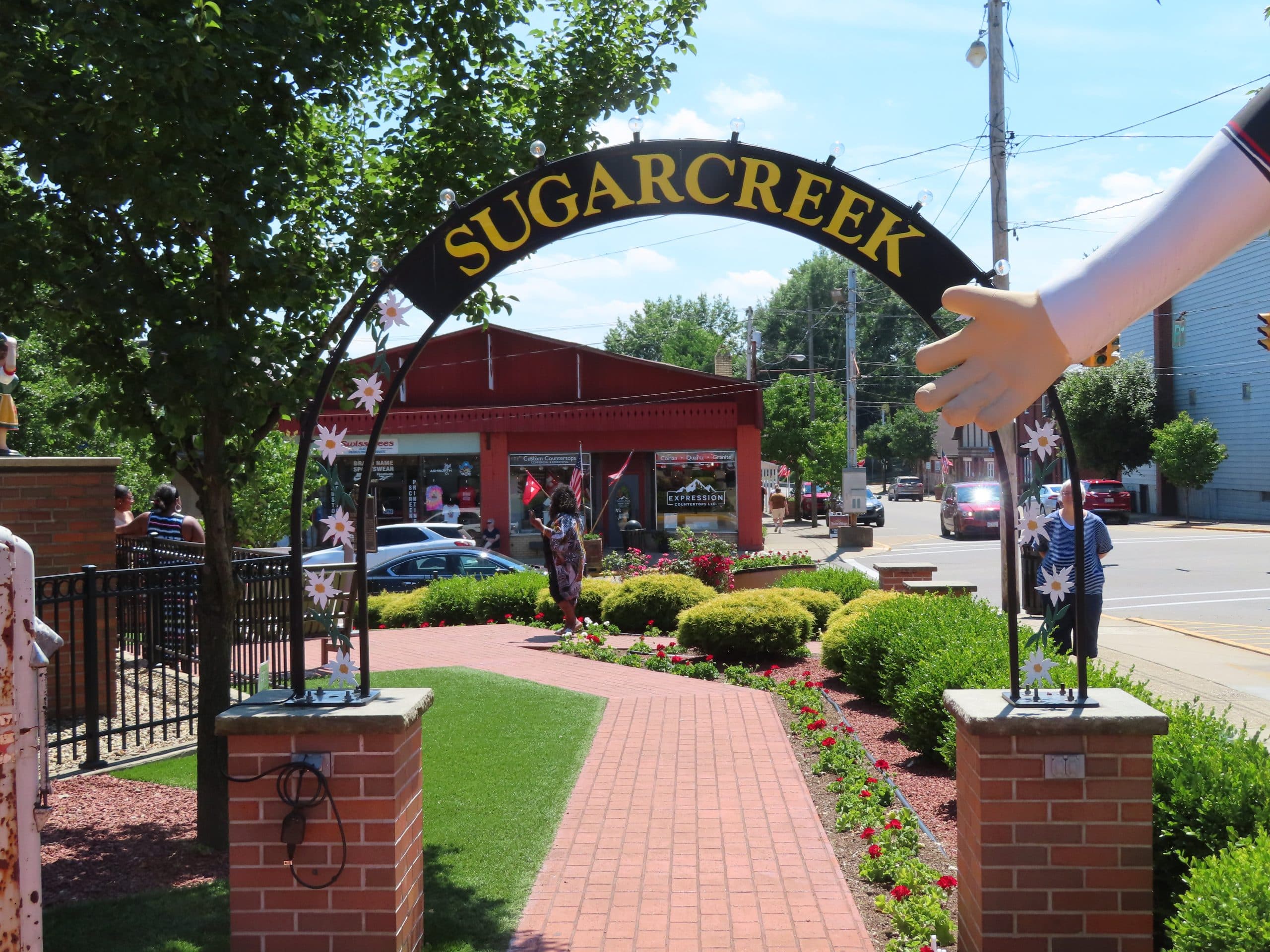 horizontal photo showing an arch with sugarcreek across the top, with a shop and street in the background Image credit: John Polak on Flickr