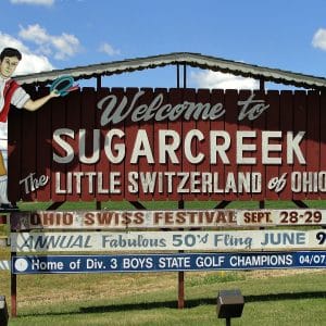 square photo showing a wooden welcome sign to sugarcreek ohio