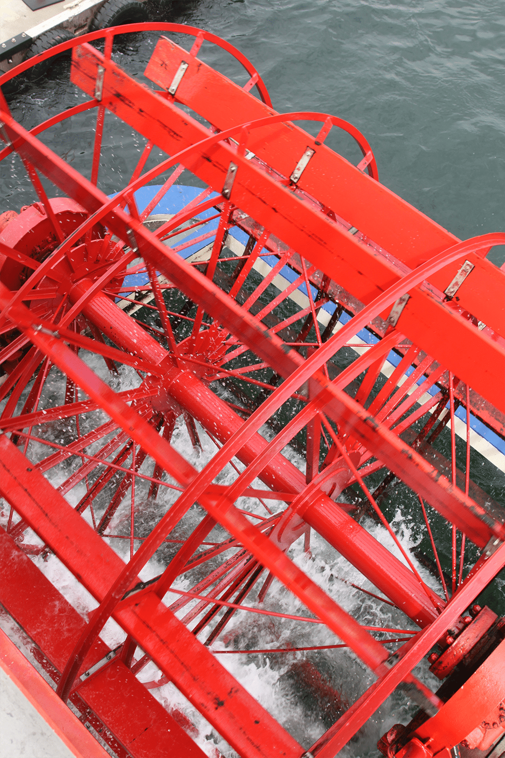 vertical photo of a red sternwheel on the water. Image via Canva Pro License