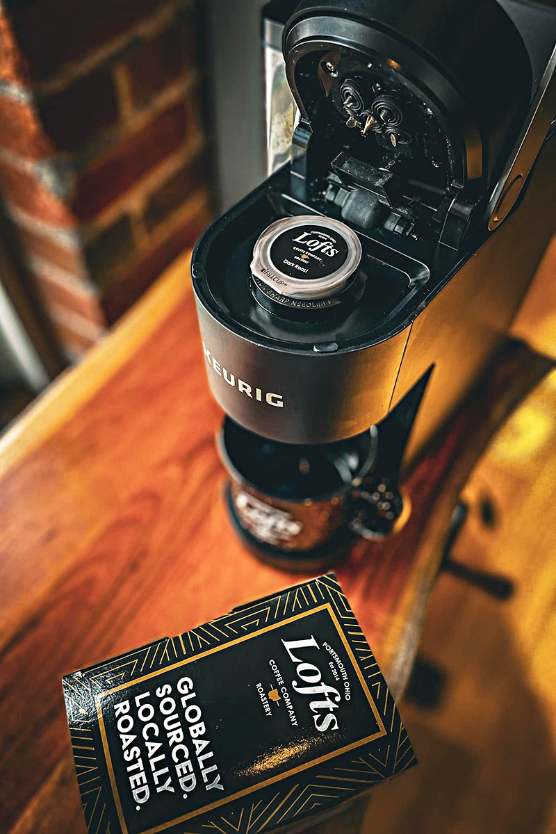 vertical image of a coffee maching and a bag of lofts coffee company coffee on a wooden surface. Image courtesy of Lofts Coffee Company & Roastery