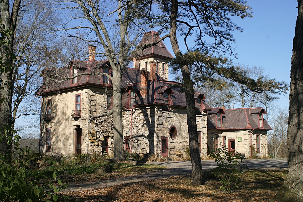 Horizontal photo of Mac-A-Cheek castle with trees and a lawn in the foreground. Image courtesy of Mac-A-Cheek. For Castles in Ohio