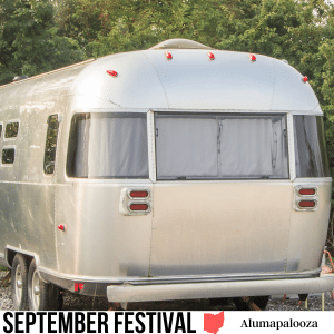 square image with a photo of the rear view of an Airstream RV camper with trees in the background. A white strip at the bottom has the text September Festival Alumapalooza. Image via Canva pro license