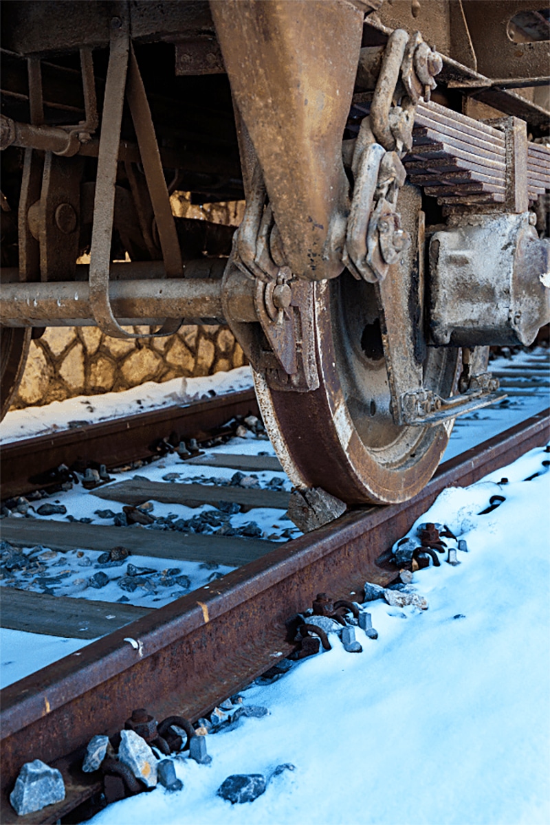 vertical photo of the wheel of a train on the track in the snow