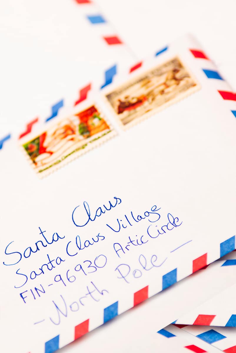 white envelopes with blue and red stripes on outside. Envelope addressed to Santa