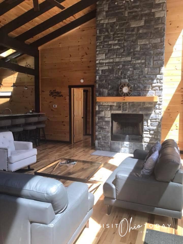 Inside of cabin with stone fire place and leather chairs and couch