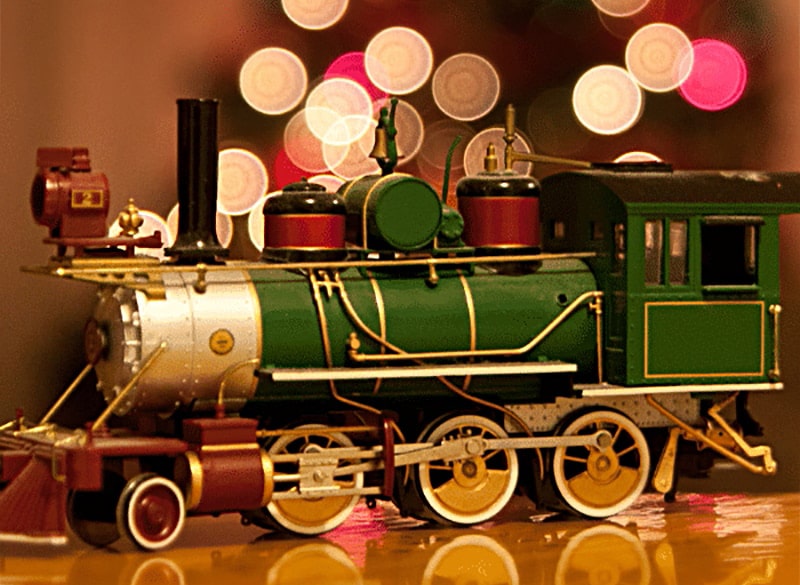 horizontal photo of a model steam train with a colorful bokeh background