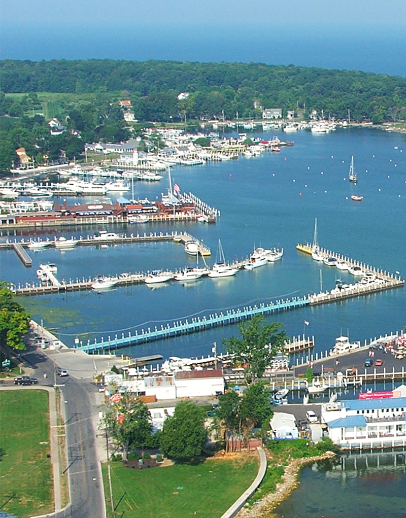 vertical photo of an aerial shot of put in bay dock area with many docked boats and a couple of boats out on the water Image via Canva pro license
