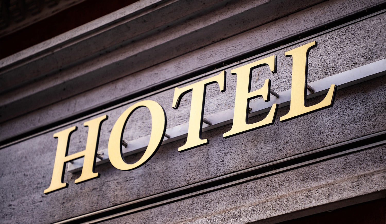 horizontal photo of a gold colored hotel sign on the front of a building. Image via Canva pro license
