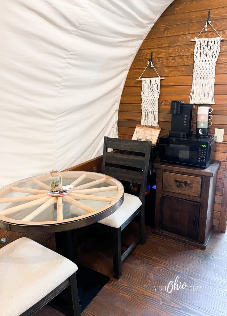 photos from inside the lux covered wagon at garystone ranch, a wheel table with two chairs, a microwave and coffee maker photo credit: Cindy Gordon of VisitOhioToday.com