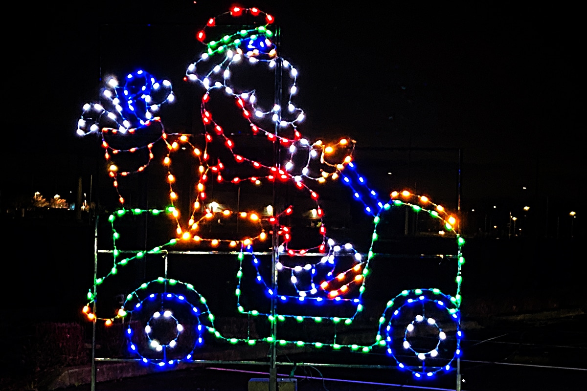 horizontal photo of a lit-up display of Santa in a car - part of drive through Christmas lights