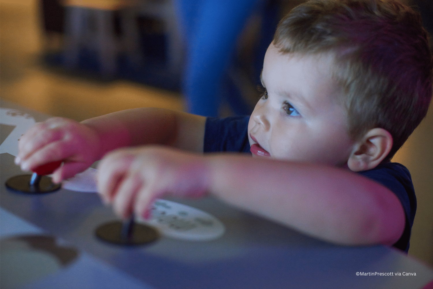 horizontal photo of a young child playing with an interactive exhibit in a children's museum