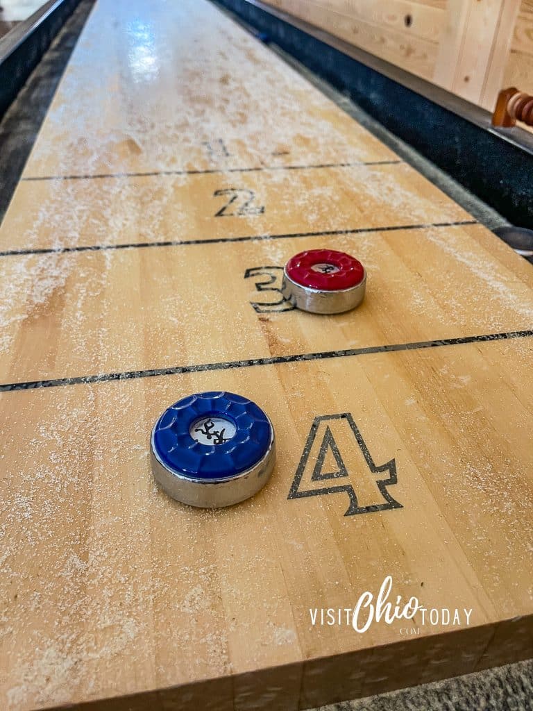 hand shuffle board table, with sand on table and red and blue puck Photo Credit Cindy Gordon of VisitOhioToday.com