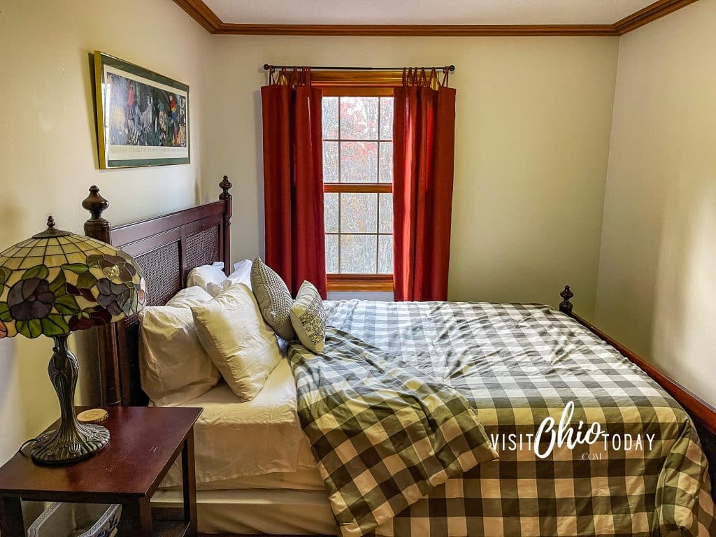 Side view of a queen sized bed in a room with red curtains