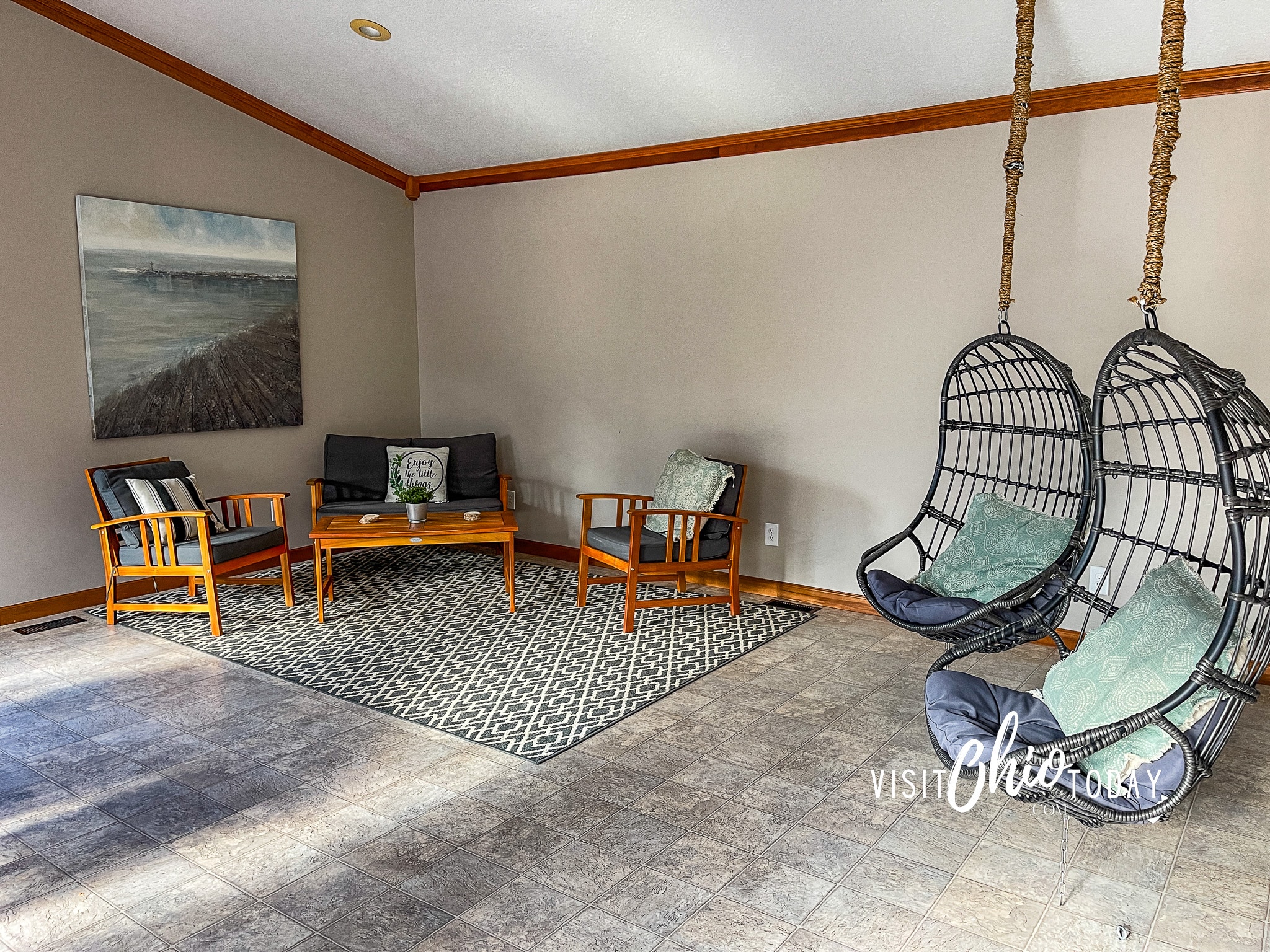 sunroom at woodlands lodge, showing two hanging chairs and a sitting area with an outdoor wooden couch, two chairs and a coffee table. Photo Credit Cindy Gordon of VisitOhioToday.com