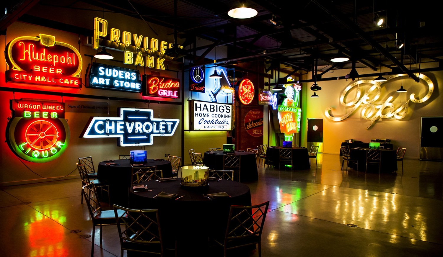 horizontal photo of the inside of the American Sign Museum with lots of lit signs and hoardings