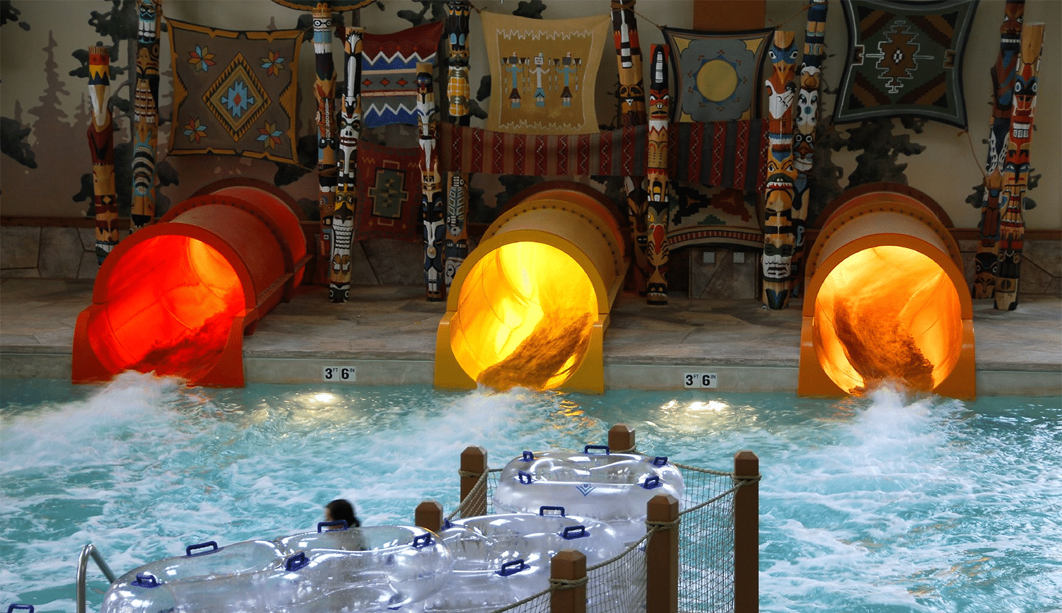 horizontal photo of 3 slides into the pool at Great Wolf Lodge Mason. A pile of tubes is in the foreground