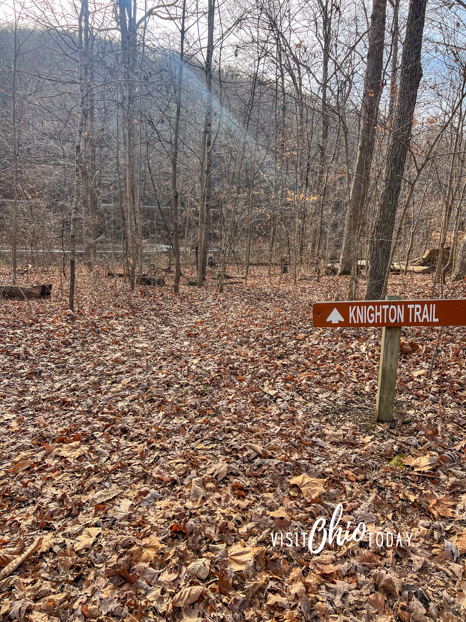 vertical photo of the Shawnee State Park with a Knighton Trail sign and the ground covered in leaves with bare trees around. Photo credit: Cindy Gordon of VisitOhioToday.com