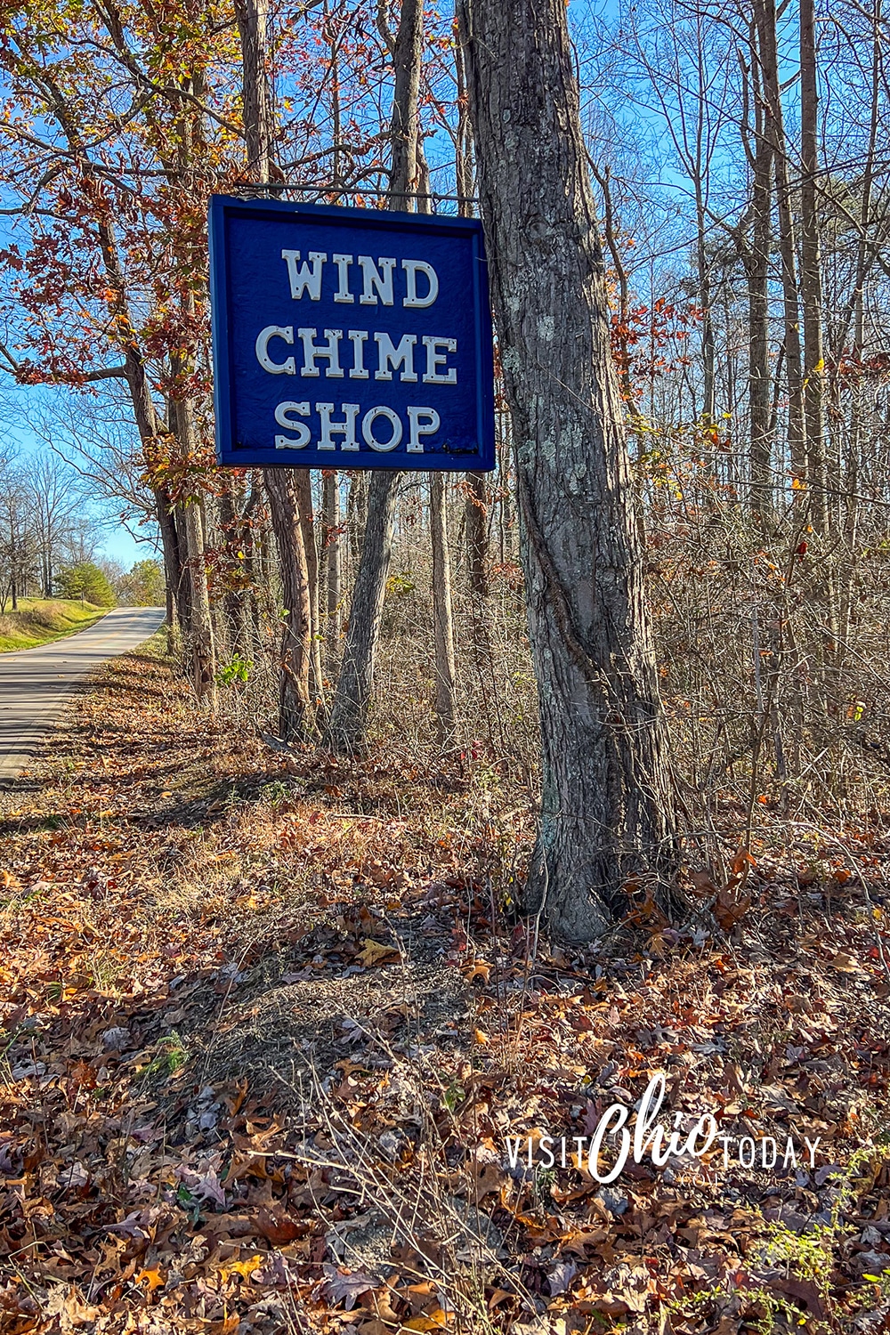 vertical photo of the road to the wind chime shop with a sign for the shop hanging on a tree. Photo credit: Cindy Gordon of VisitOhioToday.com