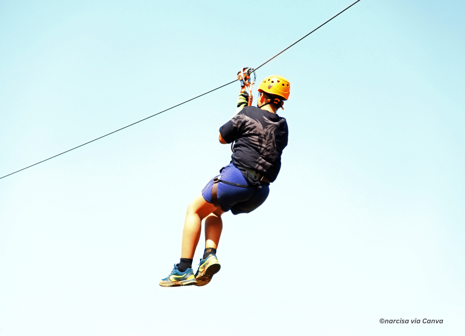 horizontal photo of a person ziplining with the sky in the background